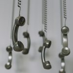 black telephone receivers hanging over gray background