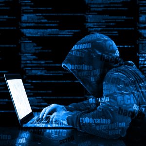 Hacker in a blue hoody standing in front of a code background with binary streams and information security terms